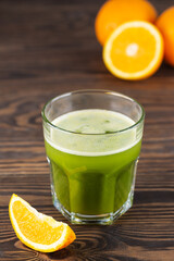 Cold matcha cocktail with orange juice on a wooden table.