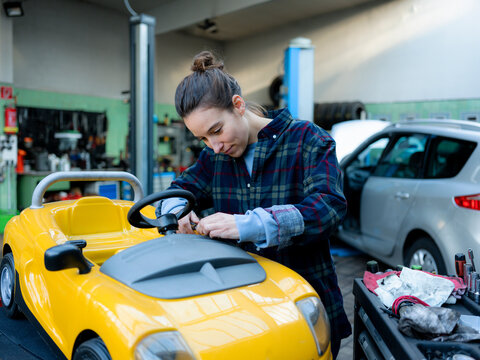 Female mechanic repairing toy car at workshop