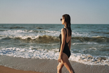 Fototapeta na wymiar cheerful woman in black swimsuit sunglasses beach walk travel