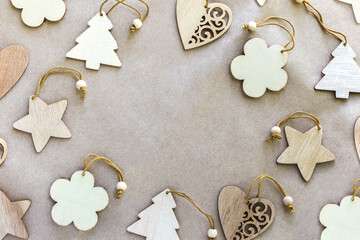 Christmas festive background from natural different wooden toys, Christmas trees, hearts, flowers and stars lie on brown craft paper in the center, place for text, top view