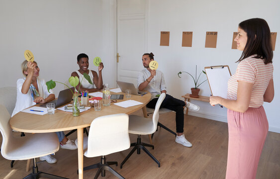 Creative business team voting through smiley papers in meeting at office