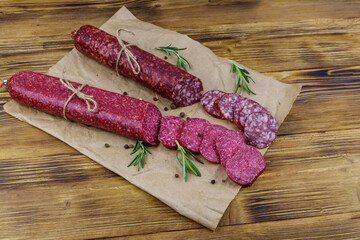 Salami sausages on craft paper on a wooden table