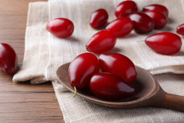 Fresh ripe dogwood berries, spoon and towel on wooden table, closeup