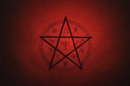 Pentagram symbol painted on paper with black paint. Occult and esoteric symbols. Spell or black magic ritual. Red color.