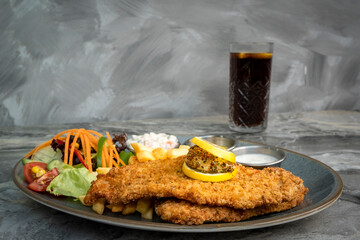 Chicken schnitzel and fried potatoes on plate over marble background. Top view, flat lay.