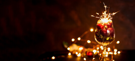 Burning bengal firework in wine glass with red Christmas balls