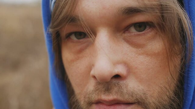 A close-up portrait of a hipster man looking at the world with a doomed sad look.