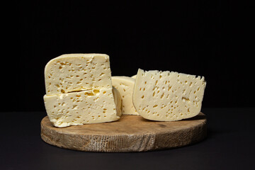 White cheese on a black background. Homemade white cheese on a wooden board. Traditional cuisine