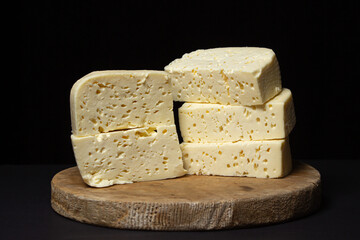 White cheese on a black background. Homemade white cheese on a wooden board. Traditional cuisine