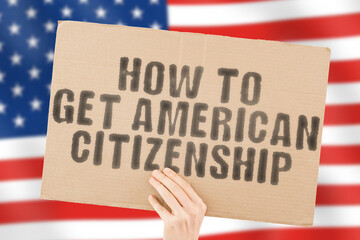 The phrase " How to get American citizenship " on a banner in men's hand with blurred American flag on the background. Dream. Family. State. Immigrant visa. Government
