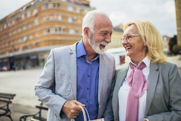 Happy senior couple walking with their shopping purchases on a sunny day