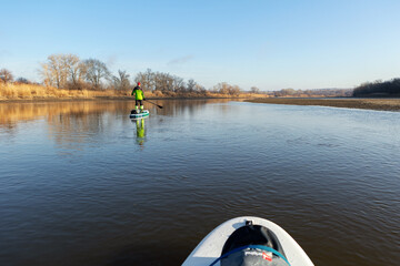 Late autumn on a clear day a man is rafting on a supboard on the river. SUP. Stand up paddle boarding