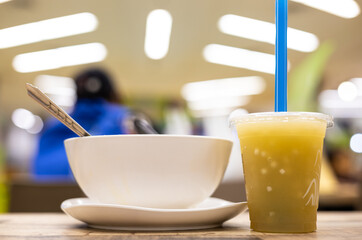 A close-up view of a plastic cup filled with cold cane juice and a white crockery.