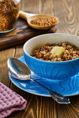 Fresh and tasty buckwheat porridge with butter in a blue cup on a wooden table