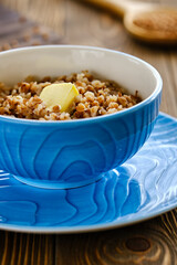 Fresh and tasty buckwheat porridge with butter in a blue cup on a wooden table