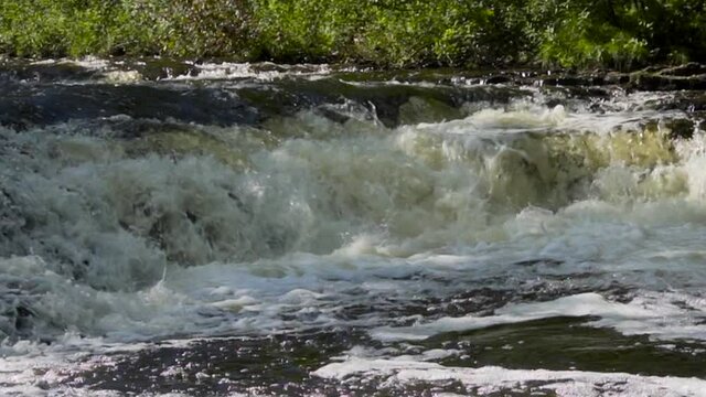Slow motion river water flowing over the rocks; Ocqueoc Falls, rushing water over rocks in Northwest Michigan after months of rain; medium view--late morning.  20 percent of real time. 435 20