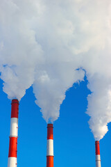 Pollution, emissions - thick smoke is coming from three pipes against the background of a clear...