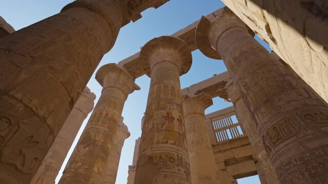 Karnak Temple in Luxor, Egypt. Majestic columns with ancient Egyptian drawings, sun comes out from behind the column