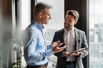 Male colleagues discussing in meeting at modern office