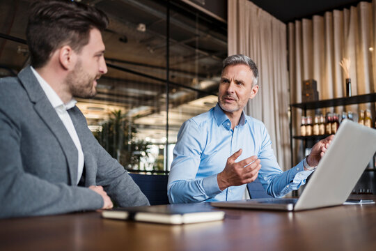 Male entrepreneurs with laptop planning strategy in board room at office