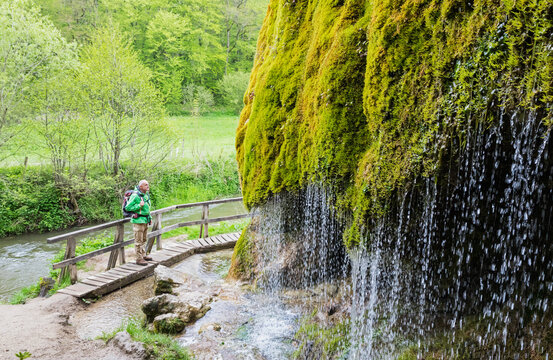 Senior hiker admiring Dreimuhlen waterfall falling down mossy slope