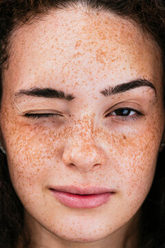 Beautiful young woman with freckles winking eye