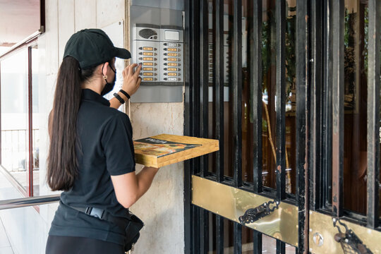 Female pizza delivery person ringing doorbell during COVID-19