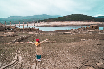 A girl explores the Galician Village Aceredo. In 1992 the village was deliberately flooded and submerged underwater. Every few years when the water levels are low, it' reappears.