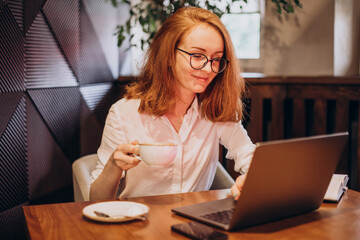 Business woman working on computer in cafe and drinking coffee