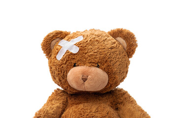 medicine, healthcare and childhood concept - teddy bear toy with medical patch on head on white background