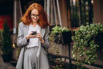 Young business woman using phone by the cafe