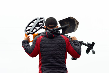 a man with a metal detector and a shovel, view from the back