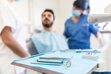 Dental equipments on tray with female dentists and male patient in background at medical clinic