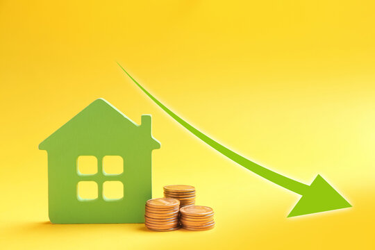 Mortgage concept. House model and coins on yellow background