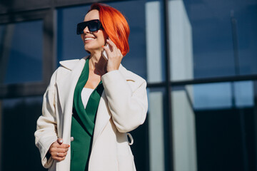 Woman in coat using phone outside the street