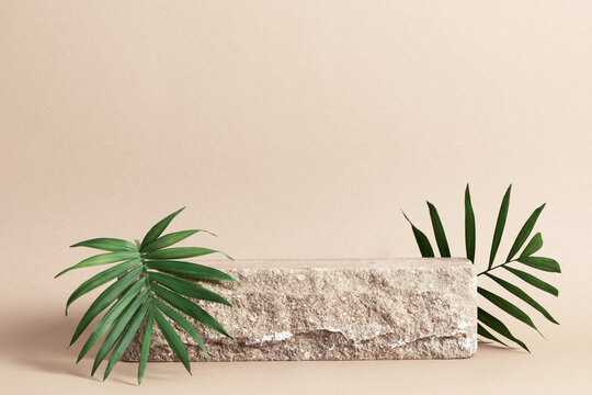 Stone podium mockup with green leaves on beige background. Front view.