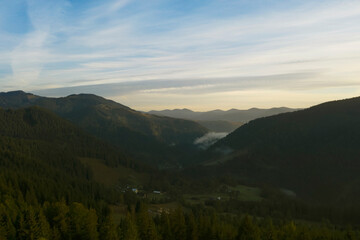 Aerial view of beautiful mountain landscape with village and green trees in morning