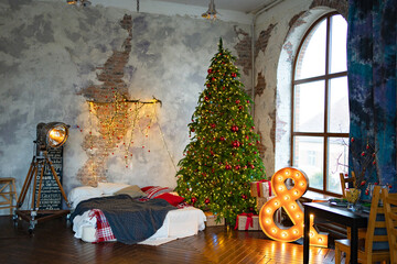 a Christmas tree in bedroom by bed with lamp shaped sign and in loft interior. 