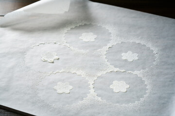 White parchment paper after sprinkling cookies with powdered sugar. Dark background, high resolution