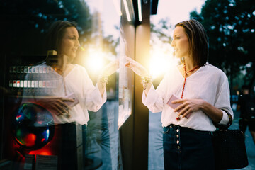 Side view of Caucasian tourist checking schedule on navigation panel tapping sensory for online...