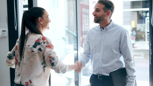 Video of happy businesswoman greeting businessman while standing in office loby.