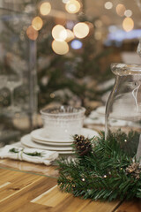 Festive christmas table setting with white plates and candles and holiday season decor.