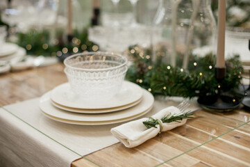 Festive christmas table setting with white plates and candles and holiday season decor.