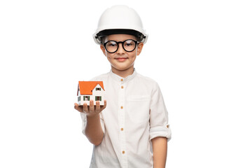 building, construction and profession concept - smiling little boy in helmet with toy house model...
