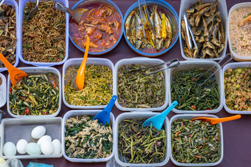 Overhead shot of people buying food over variety of delicious Malaysian home cooked dishes sold at market, Malaysia