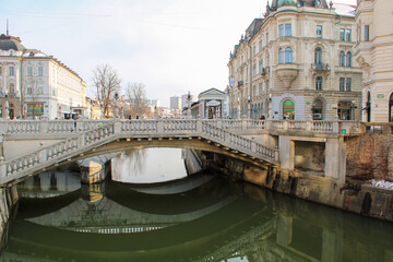Triplo ponte di Lubiana con riflessi nell'acqua del Ljubljanica e facciate con cielo