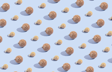 Simple pattern made of golden baubles on pastel background. Creative winter composition. Christmas party and festive concept. Minimal style.
