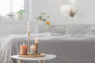 burning candles on  white table in bedroom