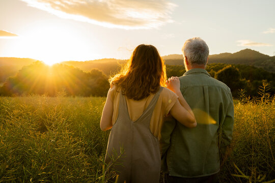 Daughter and father looking at sunset view while standing at in field