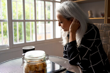 Woman with hand in hair sitting at table in living room